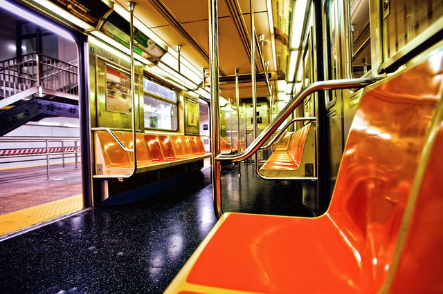 An empty IRT train car with orange seats, with the doors open